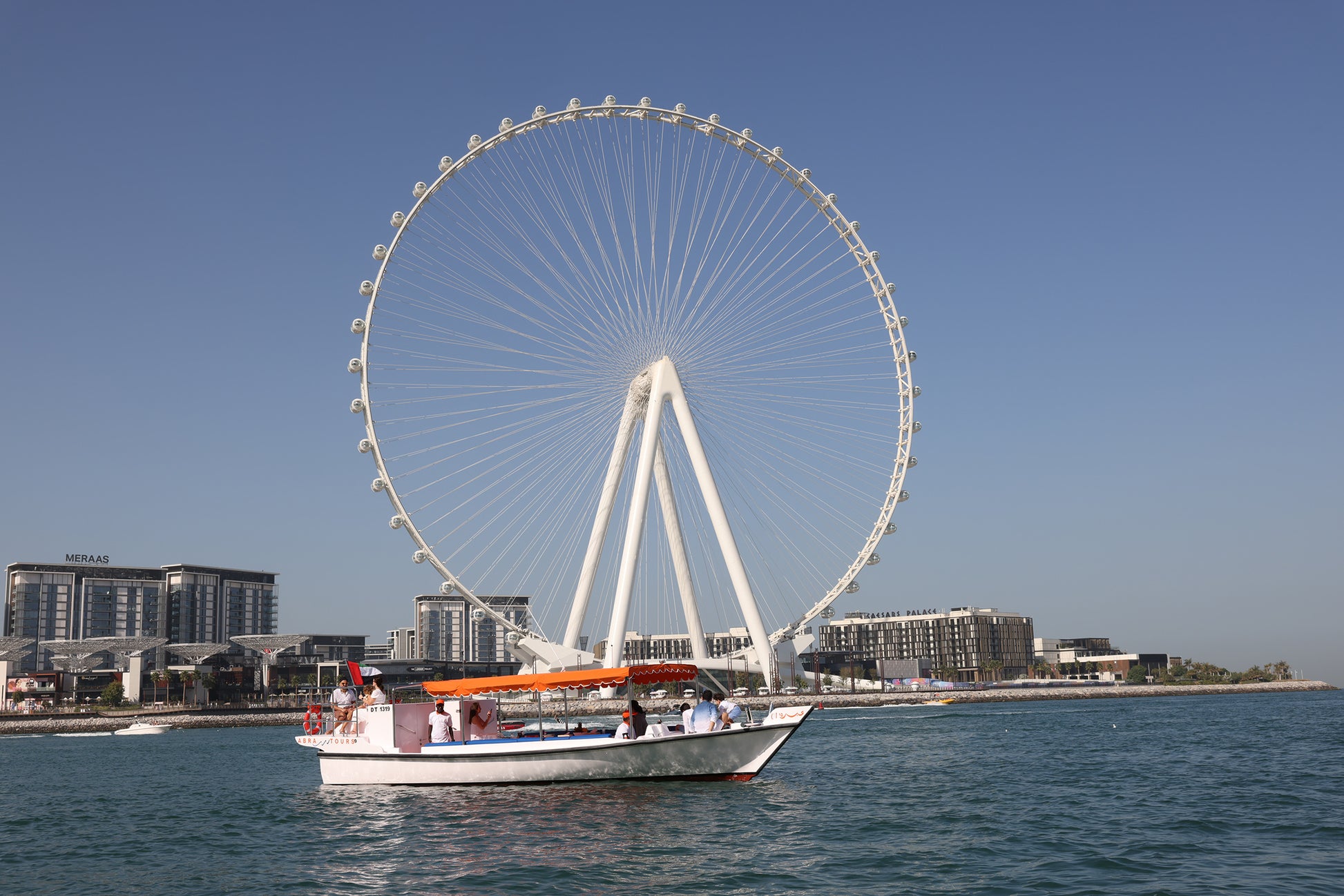 Ferris wheel with boat passing by - Dubai